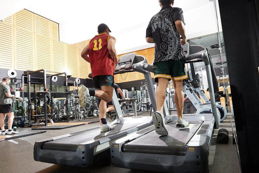 Two men running on treadmills in a gym, focused on their workout and maintaining a healthy lifestyle.