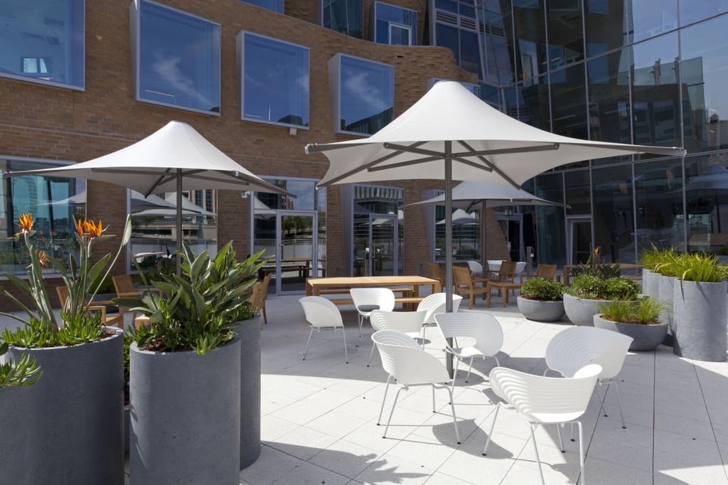 An outdoor terrace with umbrellas, large pot plants, and seating.