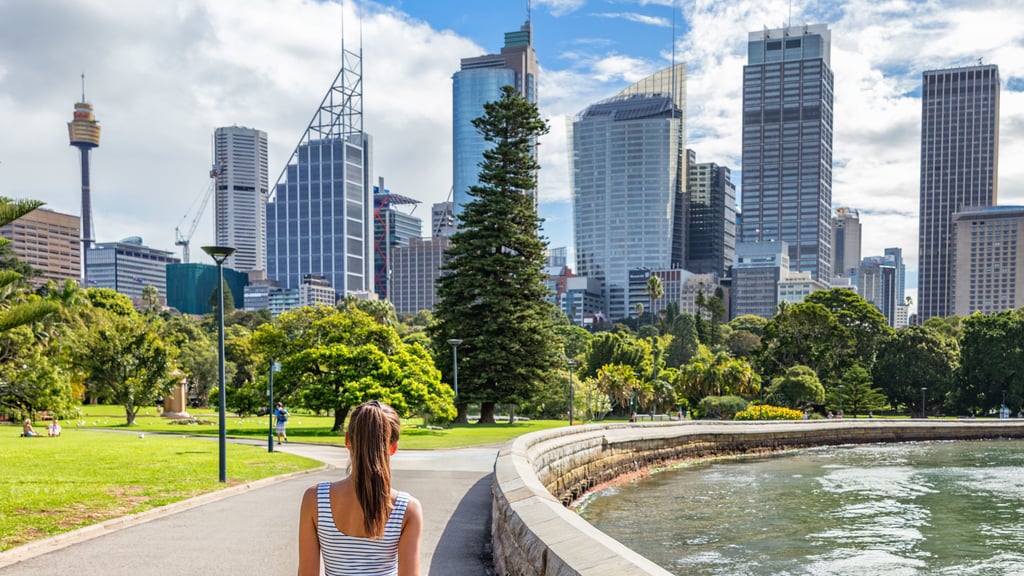 Students walks through Sydney Botanical Gardens with the city skyline in the background
