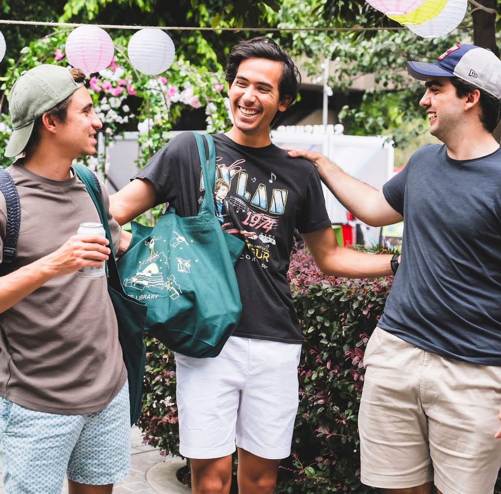 3 students on the UTS campus smiling with arms around shoulders