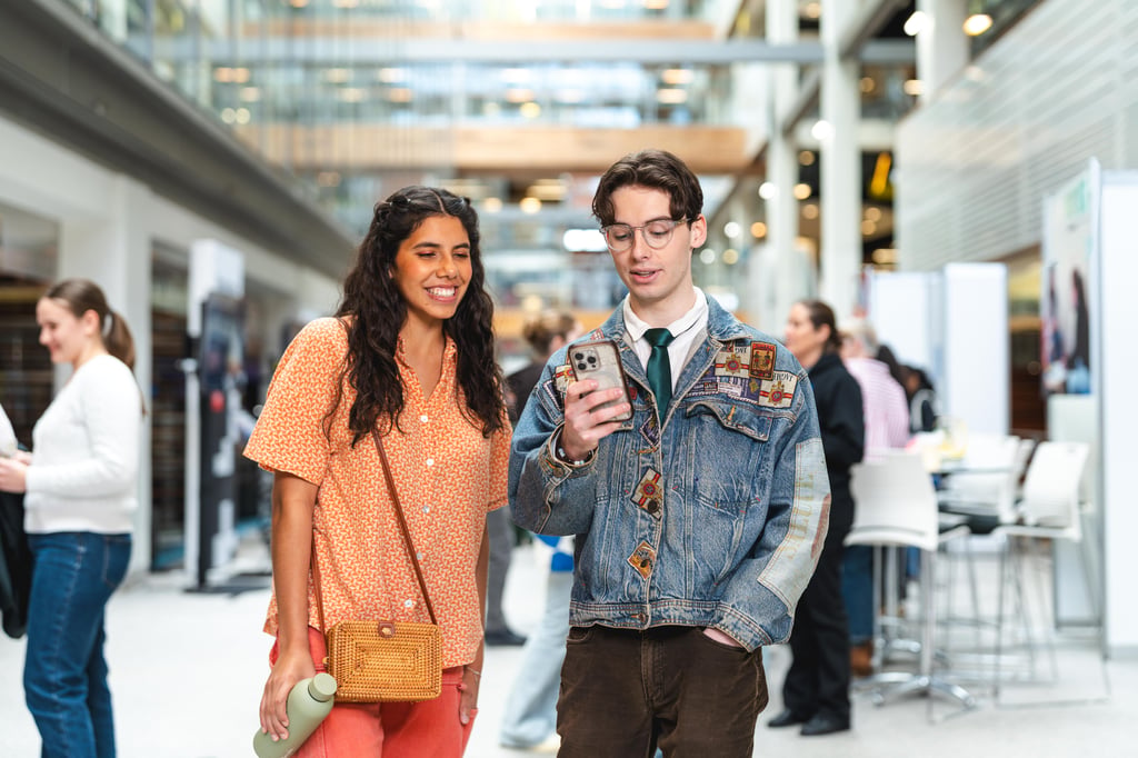 Two prospective students viewing information on a smartphone while exploring the UTS campus during Open Day.