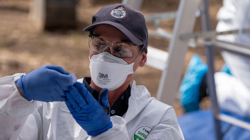 Person in a hazmat suit and protective glasses conducting tests.