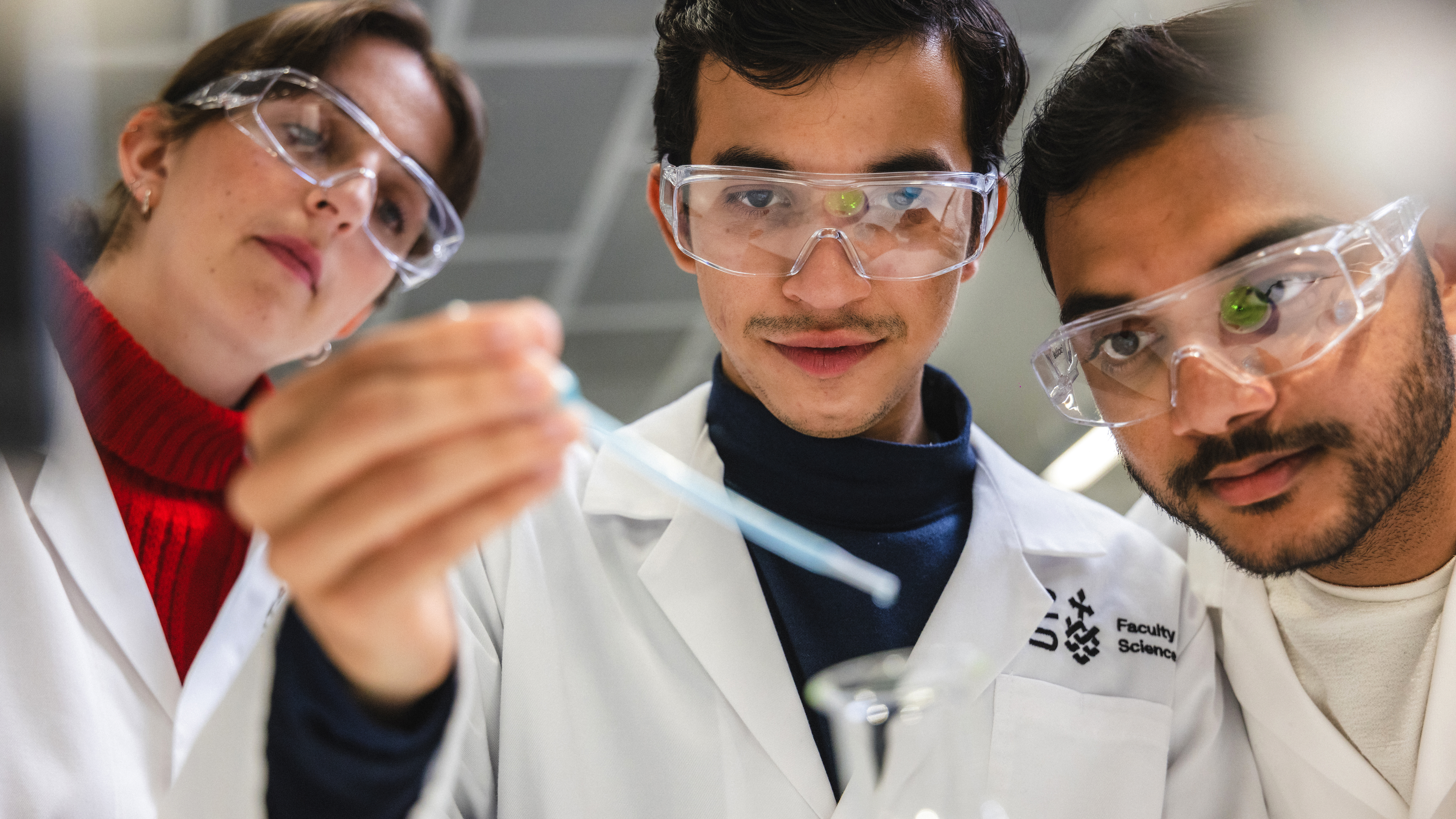 One female and two male students doing an experiment in a UTS science lab. Middle student is holding a pipette and students next to him are observing.