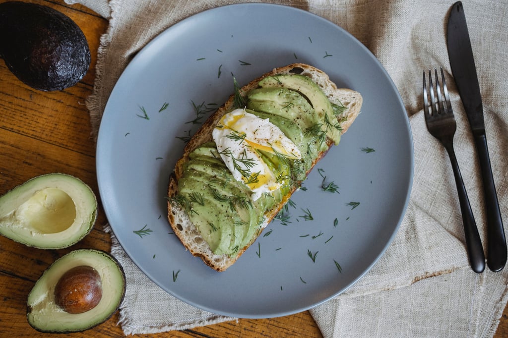 Top down view of sliced avocado on toast, with a cut avocado on the side.