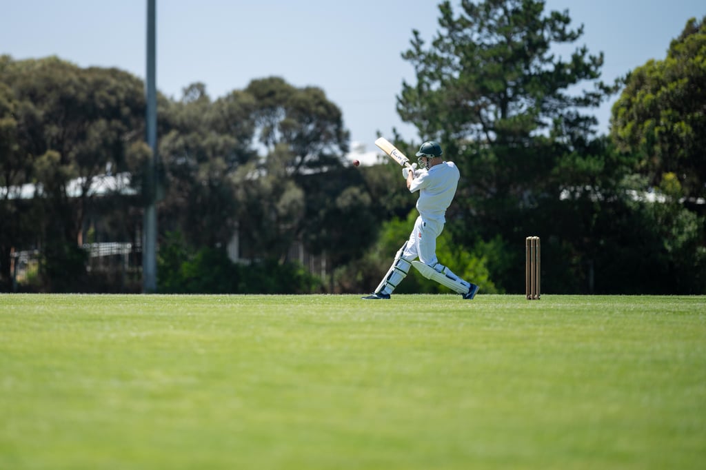 A cricketer batting on pitch on a green oval in Australia