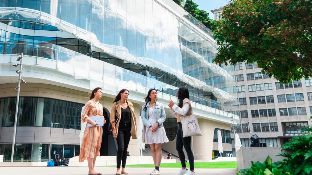 A group of students engaged in conversation on the UTS campus, in front of the Alumni Green.