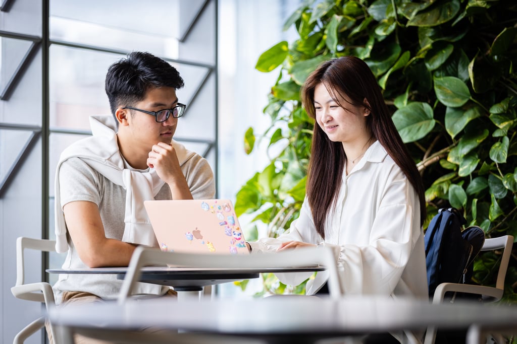 Two students discussing their assignments in a light-filled building on the UTS Campus.