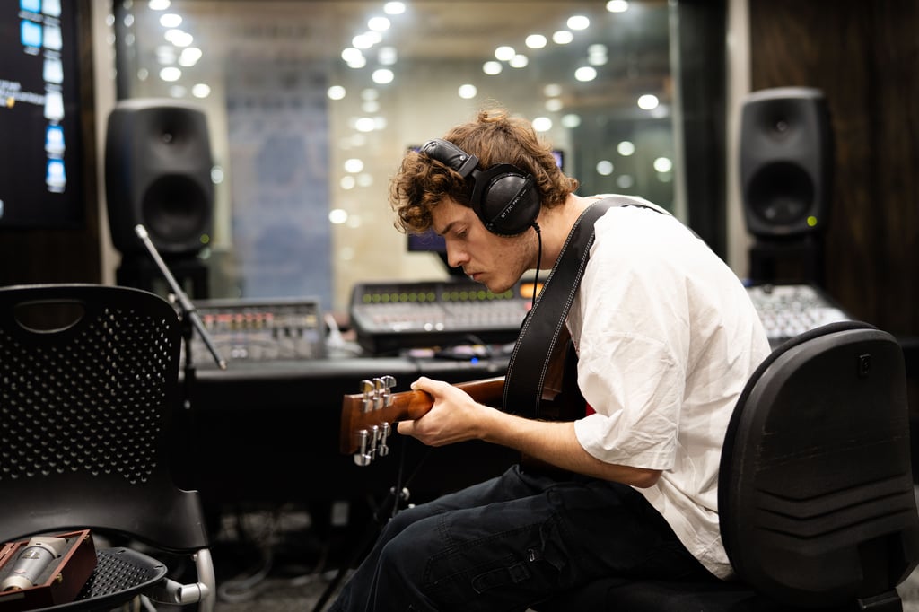 Student in sound room with guitar.