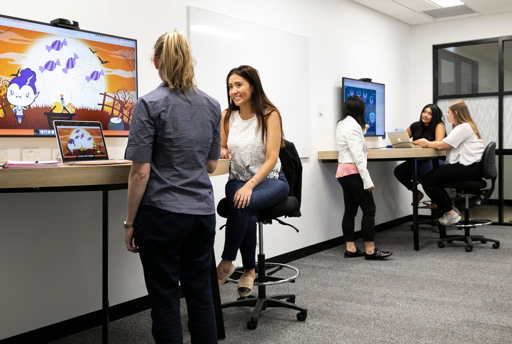 Two groups of people collaborate in a large meeting room.