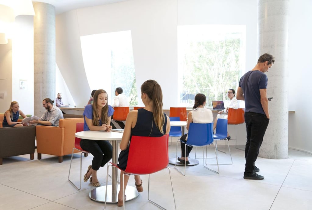A group of people sitting at various tables in a group collaboration area.