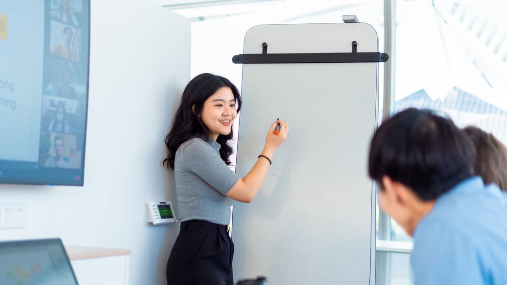 Student in the library writing on a whiteboard during a hybrid workshop