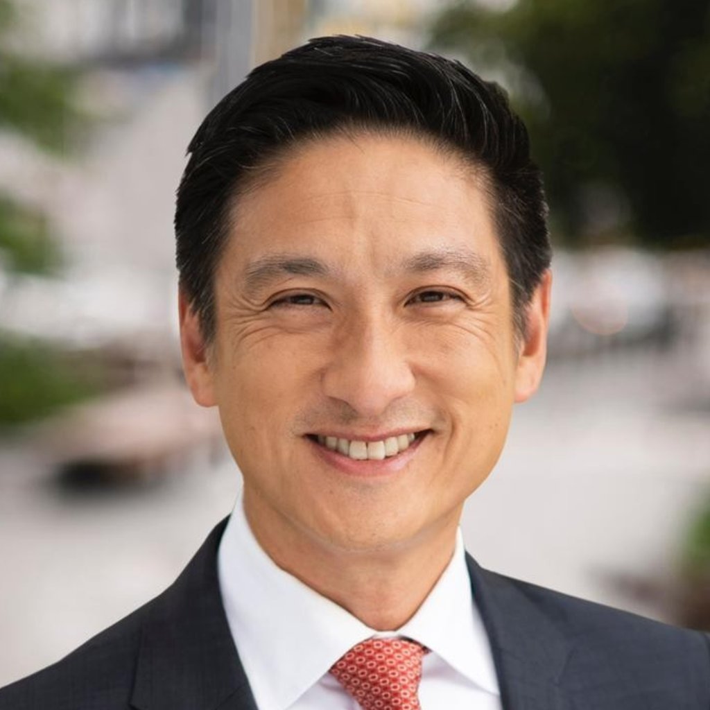 Man in a grey suit and white shirt smiling
