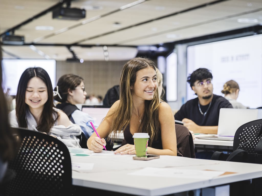 University of Technology Sydney students smiling while sitting at desks in a seminar