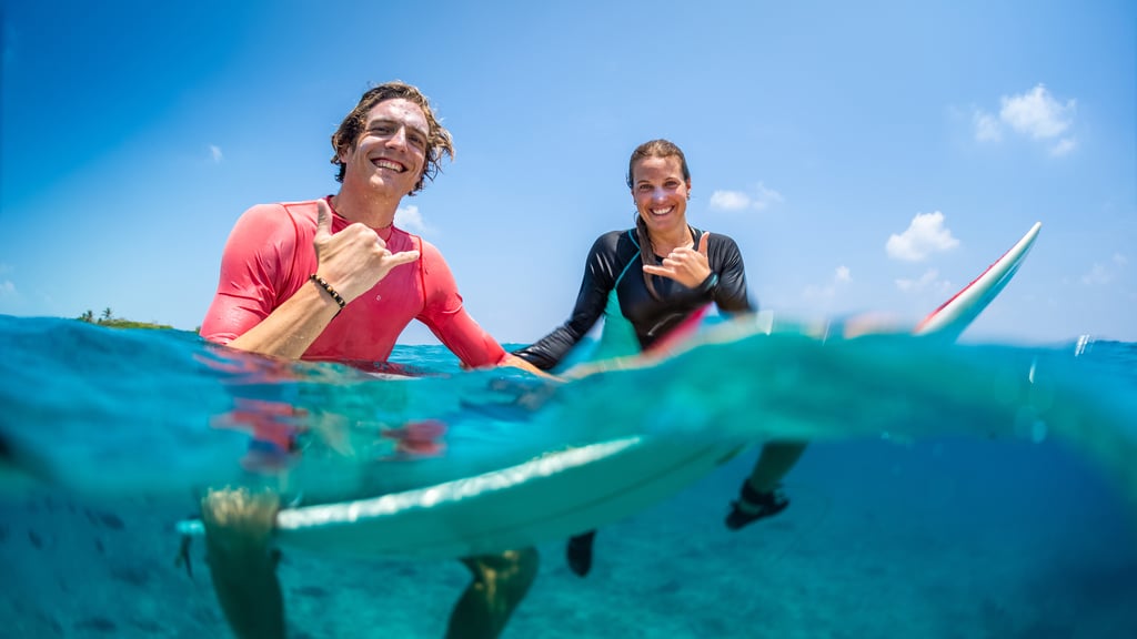 Two young happy surfers sitting on the surfboards in the water