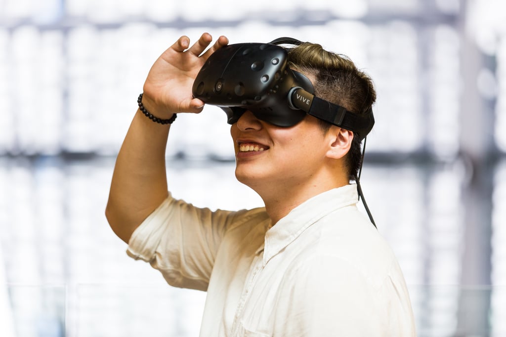 Engineering student with Virtual Reality (VR) glasses smiling at what he is looking at.