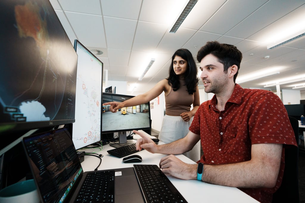Two UTS Rapido Software engineers collaborating at a desk looking at software projects on screen
