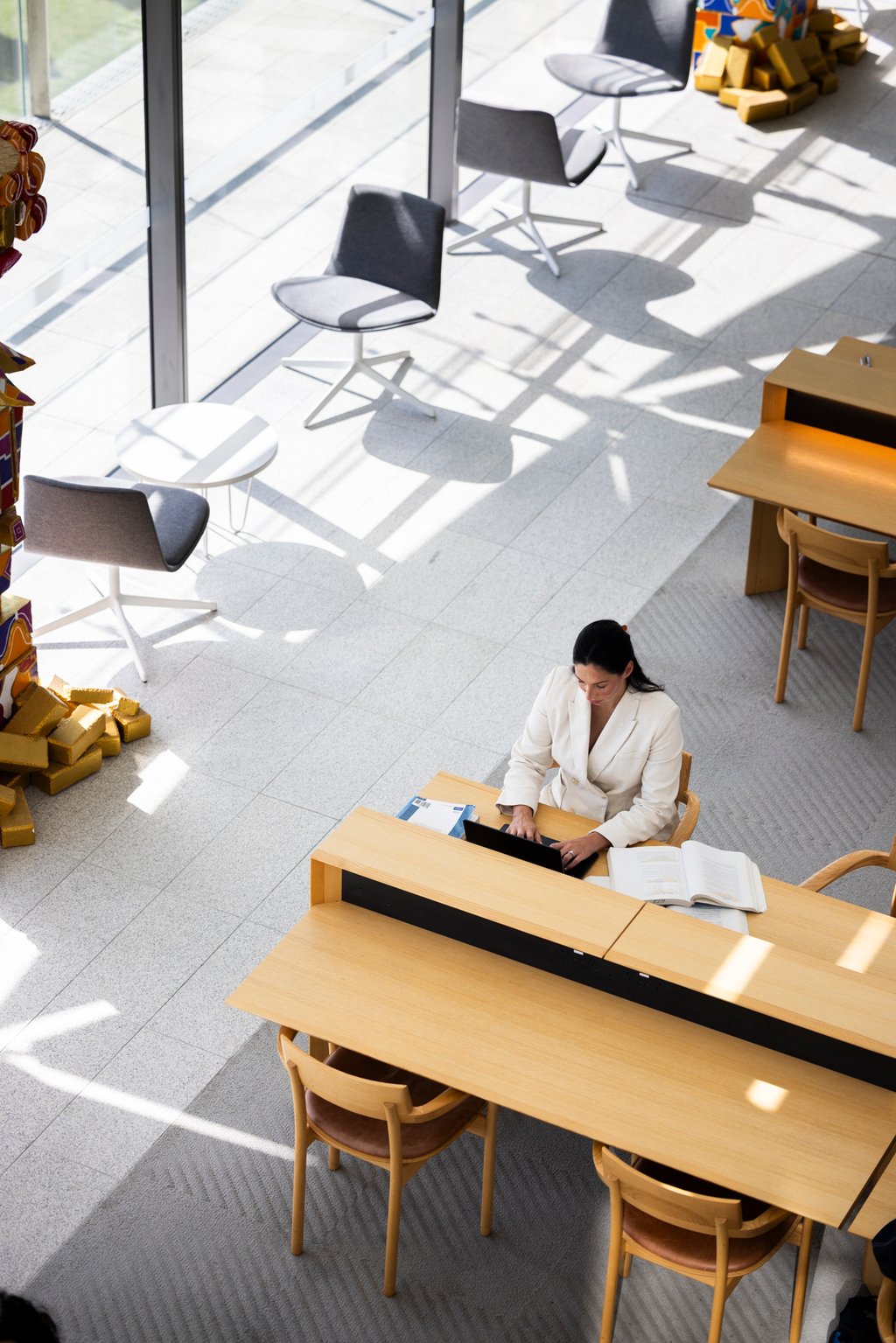 A view from above shows Samantha, wearing a white blazer, working at her laptop.