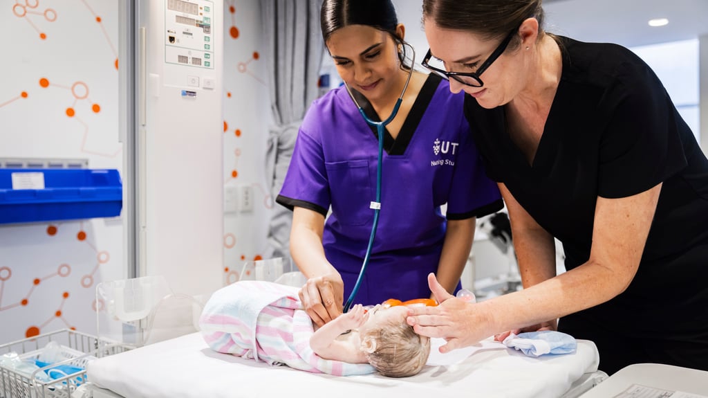 Two student nurses practising on a dummy baby