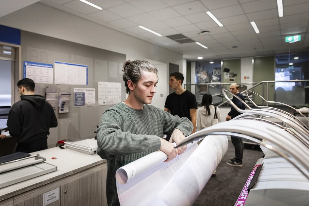 University student using a large printer in a computer lab