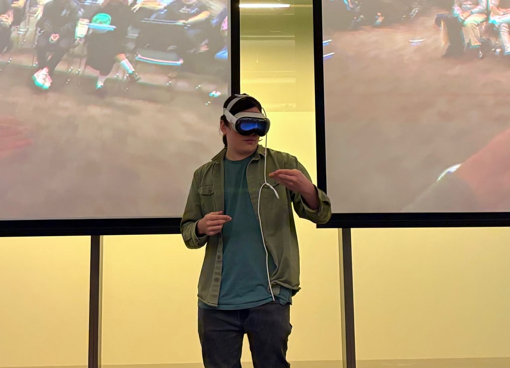 A man using a VR headset in front of two large screens.