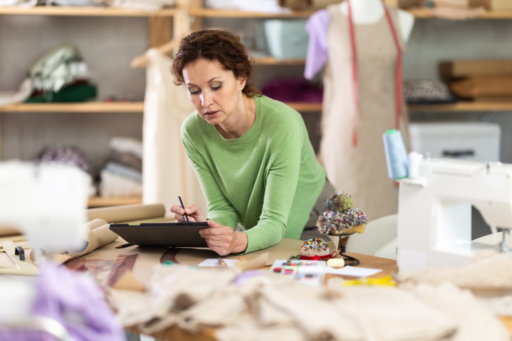 Woman tailor creates sketch of dress on tablet, draws and visualizes model of clothing using computer technology. Software for drawing and visualization. Picture: JackF/Adobe Stock