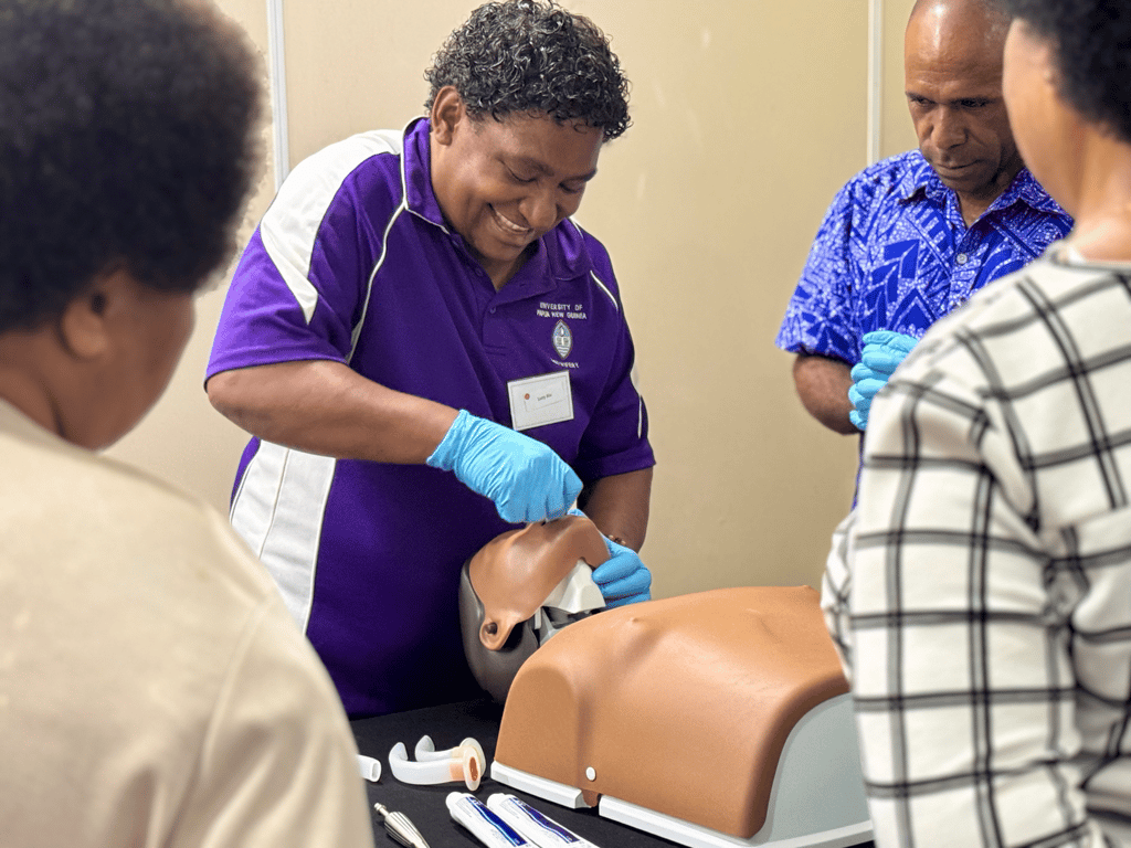 The group undertake a training activity on a medical mannequin.