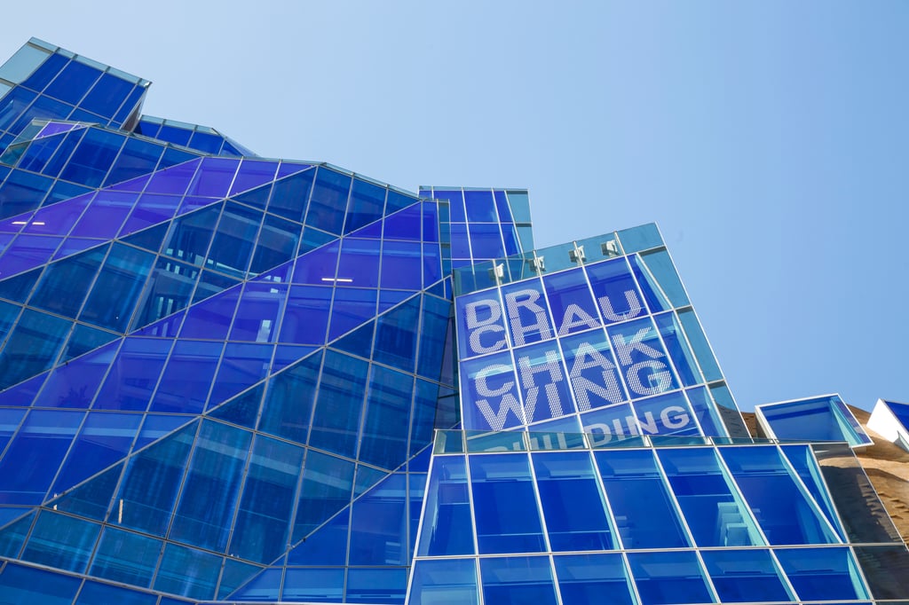 Architectural view of the UTS Chau Chak Wing Building featuring angular blue glass panels and large signage displaying the building’s name.