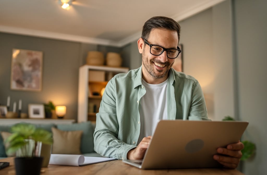 Man smiling while working on a laptop.