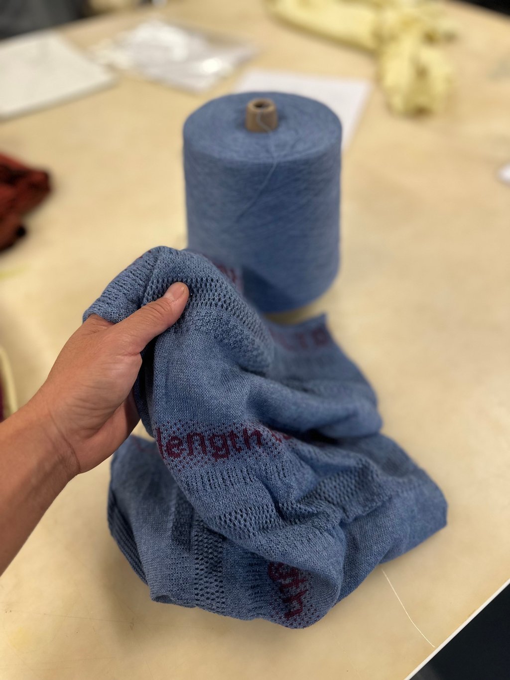 A hand touching the recycled yarn knitted sample.