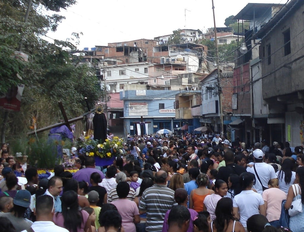 Street level image of a street in Caracas that is crowded with people in a procession.