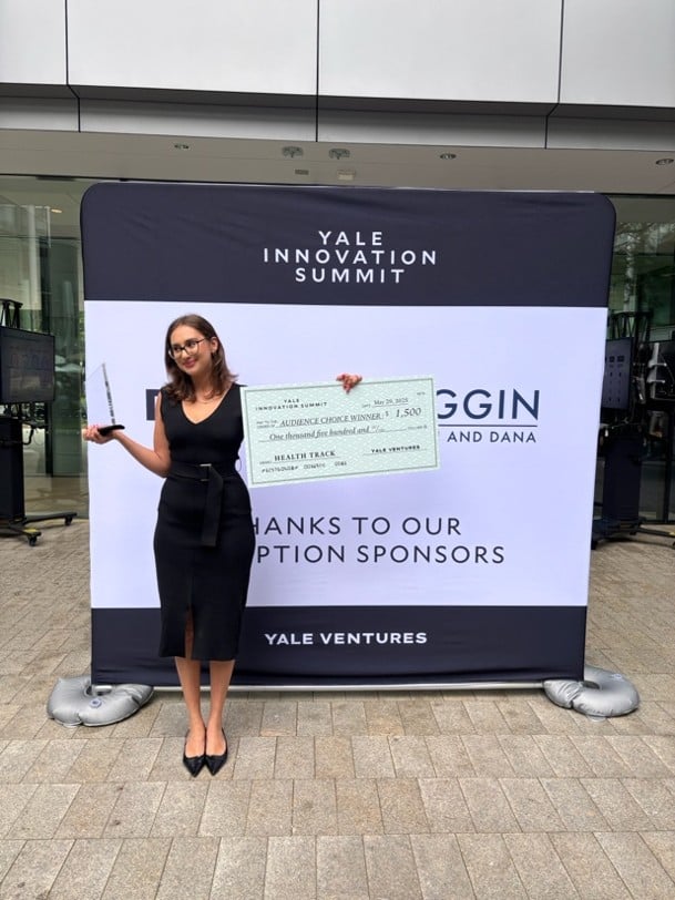 Jaya wins the Audience Choice at the Yale Innovation Summit 2025. She stands with her trophy and a large cheque.