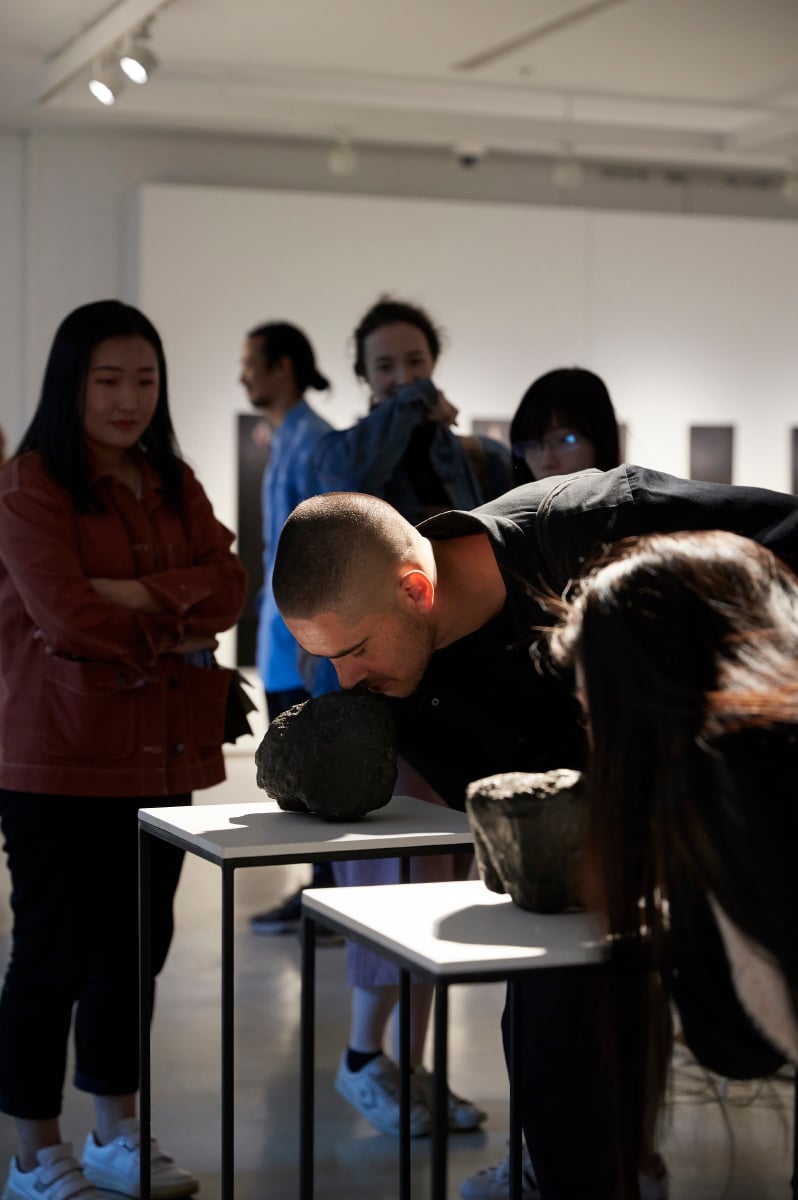 Art enthusiasts examine a sculpture in an exhibition space, reflecting on its form and the artist's intent.
