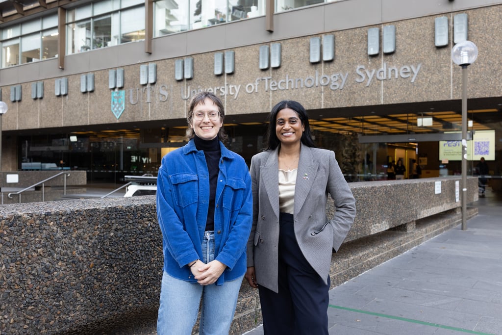 Ash, wearing a grey blazer meeting with Dr Kathryn Greenman, wearing a dark blue denim jacket, outside the main UTS building, smiling