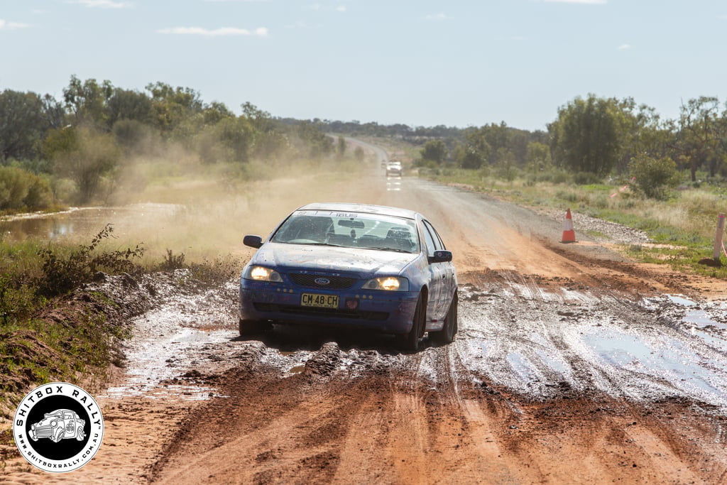 Shitbox Rally car driving through dirt roads and water