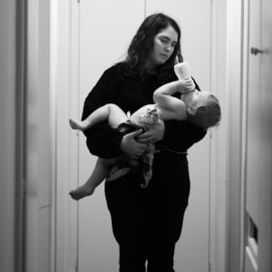 Mother holding a baby while they drink from a bottle.