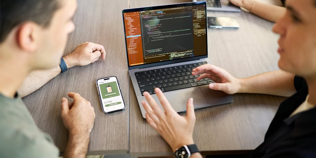 Two people having a discussion with their laptop and phone on the table in the background