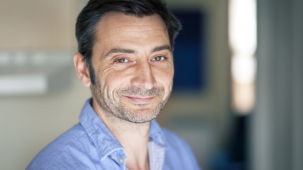 Man in a blue shirt, smiling.