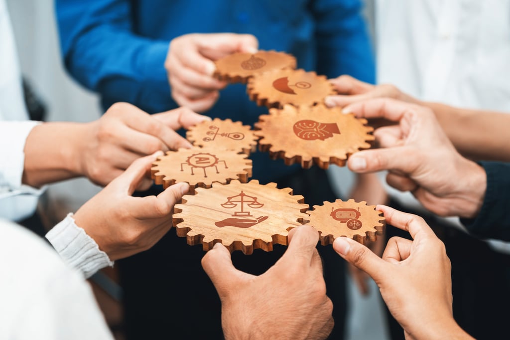 This conceptual image illustrates a diverse team working together, using wooden gears to symbolize collaboration, ethics, and innovative solutions in business practices. Picture by InfiniteFlow/Adobe Stock