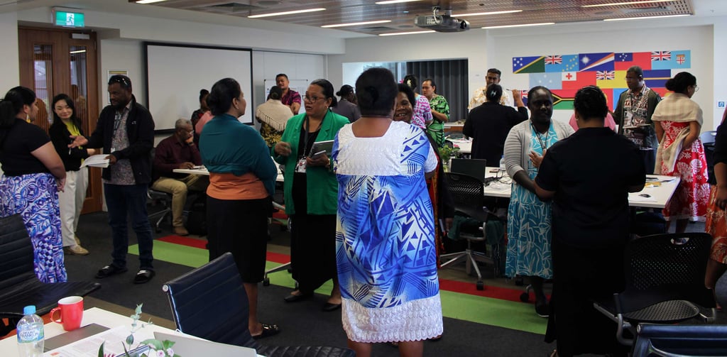 About 20 people stand in pairs talking to each other in a large training room.