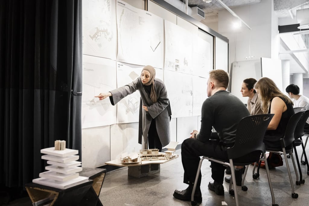 A small group of university students being shown design plans on a wall