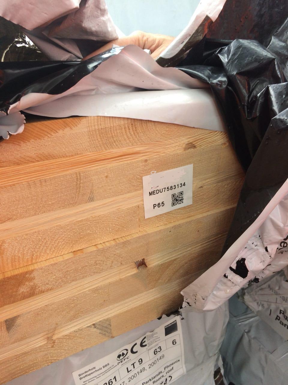 A close up of prefabricated timber with its plastic pulled aside showing its QR code.