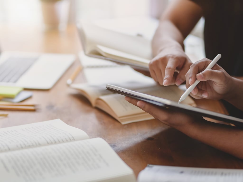 Closeup of two people studying together using books and electronic devices. Picture: Adobe Stock