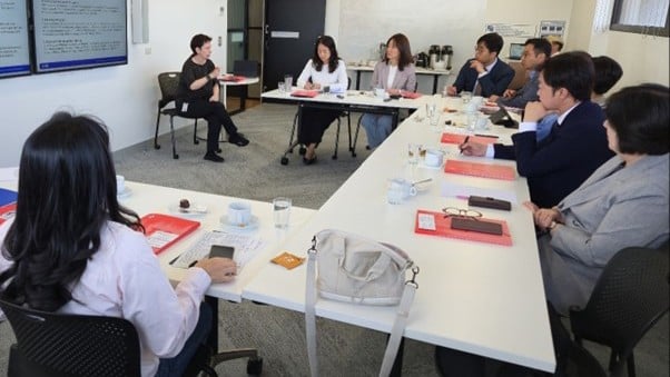 Members of the delegation from the Yuseong-gu Council and LGC members seated at tables in a three sided configuration looking at an electronic whiteboard during a workshop on the visit.