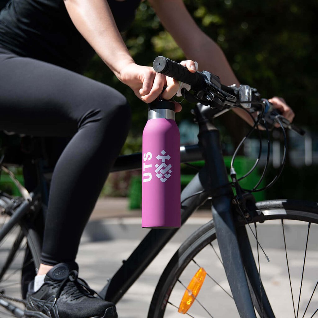 Person riding a bike with a UTS drink bottle in hand