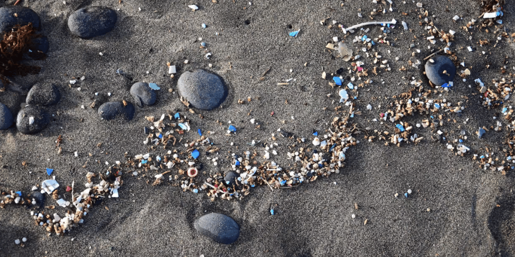 Small pieces of colourful plastic debris scattered among rocks and sand on a beach.
