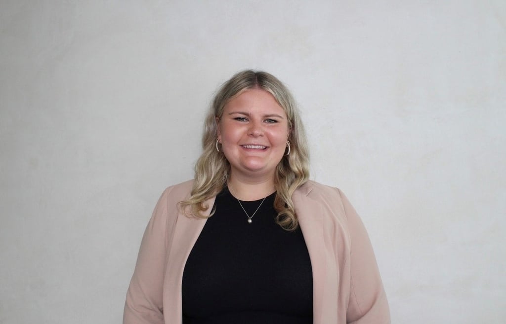 Georgina Hedge, a UTS LLB student, smiling at the camera wearing a black top and pink cardigan.