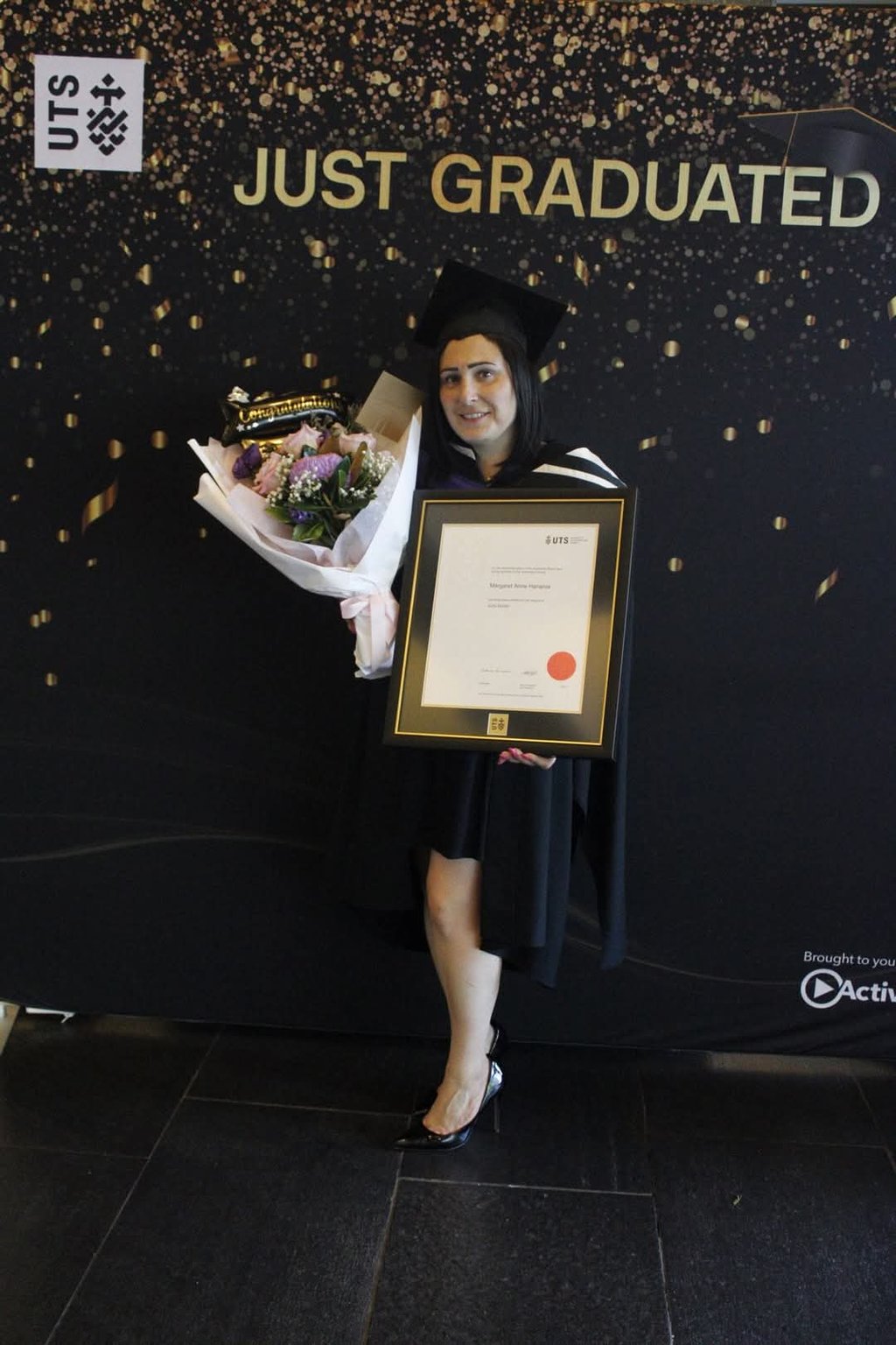 Photo of Margaret Hanania with a bunch of flowers and her JD certificate