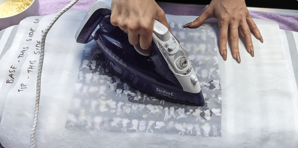 Person using an iron to transfer a decorative design onto fabric.