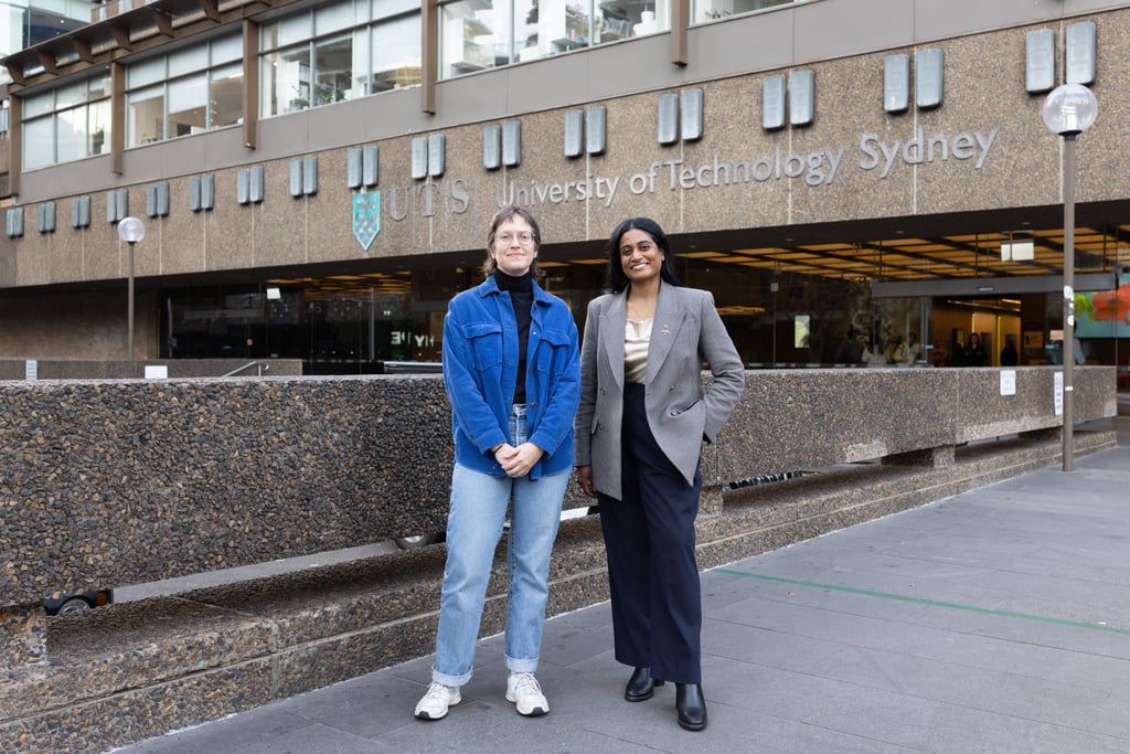 Ash, wearing a grey blazer meeting with Dr Kathryn Greenman, wearing a dark blue denim jacket, outside the main UTS building, smiling