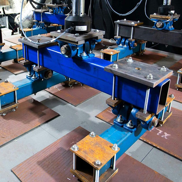 Floor panels being tested by heavy machinery in a lab.